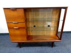 A mid century teak sliding glass door bookcase fitted with bureau and two drawers on raised legs
