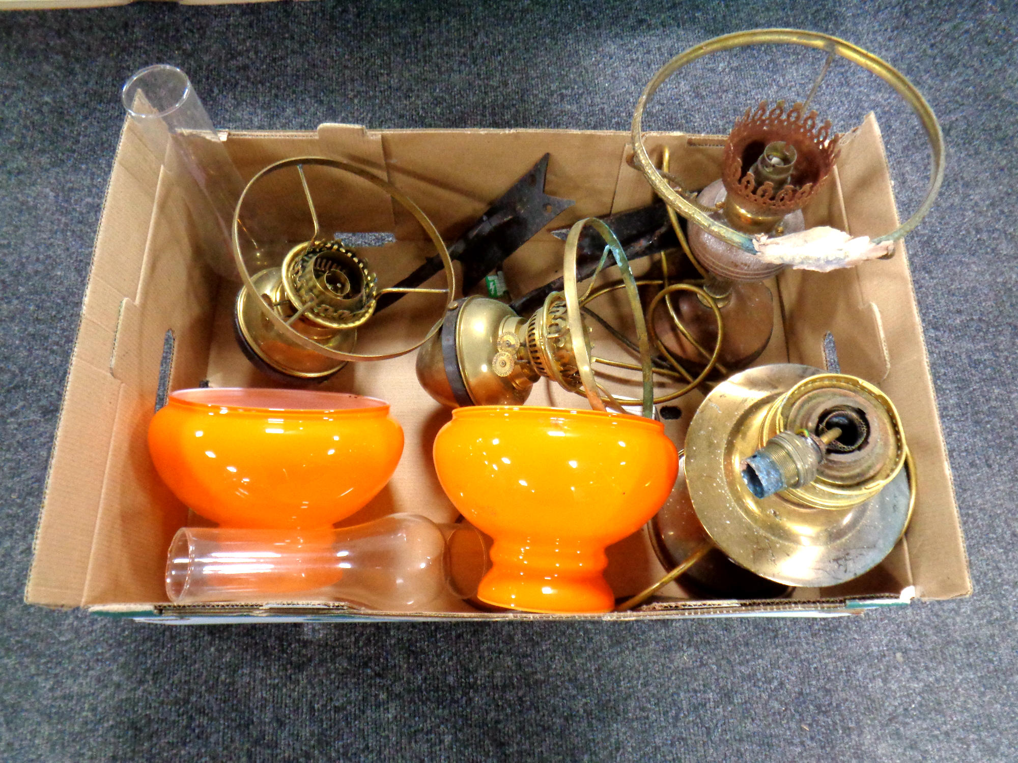 A box of pair of brass paraffin wall lights with cast iron brackets, orange shades and chimneys,