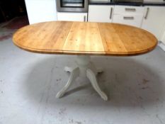 An oval pine extending dining table with leaf on painted pedestal together with two sets of three