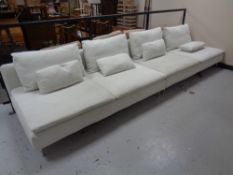 A contemporary twin-section settee with scatter cushions, on chrome legs.