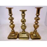 A pair of brass candlesticks together with another single example