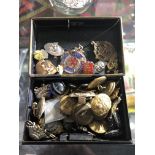 A vintage metal tin containing military badges and buttons,