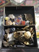 A vintage metal tin containing military badges and buttons,