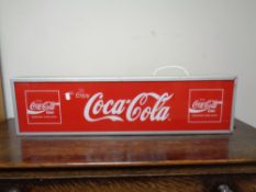 An illuminated Coca Cola advertising sign.