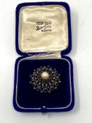 A vintage circular brooch set with diamonds pearls and garnet, stamped 18ct.