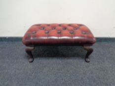 A Burgundy buttoned leather foot stool.