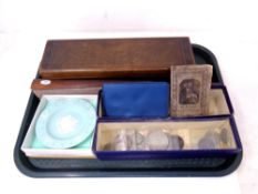 A wooden box containing pencils and drawing items, a wooden hand fan, some coins, ceramic dish.