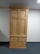 A pine double door wardrobe fitted with three drawers.