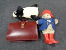 A leather satchel together with a Paddington Bear and a Shaun the Sheep hot water bottle case.