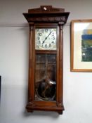 An Edwardian oak wall clock with pendulum and two weights