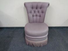 An upholstered bedroom chair with button back.
