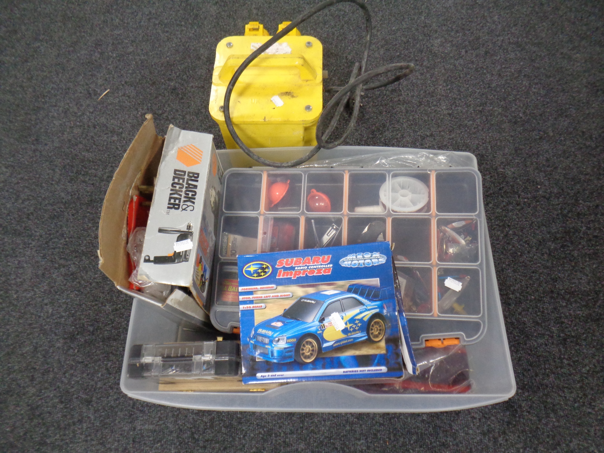 A box containing fishing lures, a drill bit set, Black and Decker electric drill,