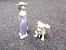 A Nao figure of a puppy together with a Lladro figure of a lady in a purple dress.