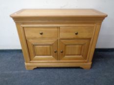 A contemporary light oak side cabinet fitted with two drawers.