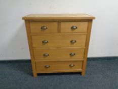 A contemporary light oak five drawer chest.