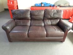 A brown leather upholstered three-seater settee