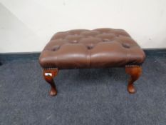 A studded brown leather foot stool.