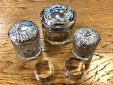 Three silver-lidded cut glass dressing table pots, together with two silver napkin rings.