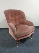 A Victorian style buttoned armchair upholstered in pink fabric.