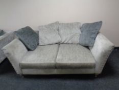 A pair of fabric two seater settees upholstered in grey fabric with two tone scatter cushions.