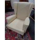 A 20th century wing backed armchair in cream upholstery