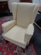 A 20th century wing backed armchair in cream upholstery