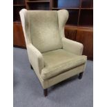 A continental wing back armchair upholstered in green Dralon