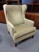 A continental wing back armchair upholstered in green Dralon