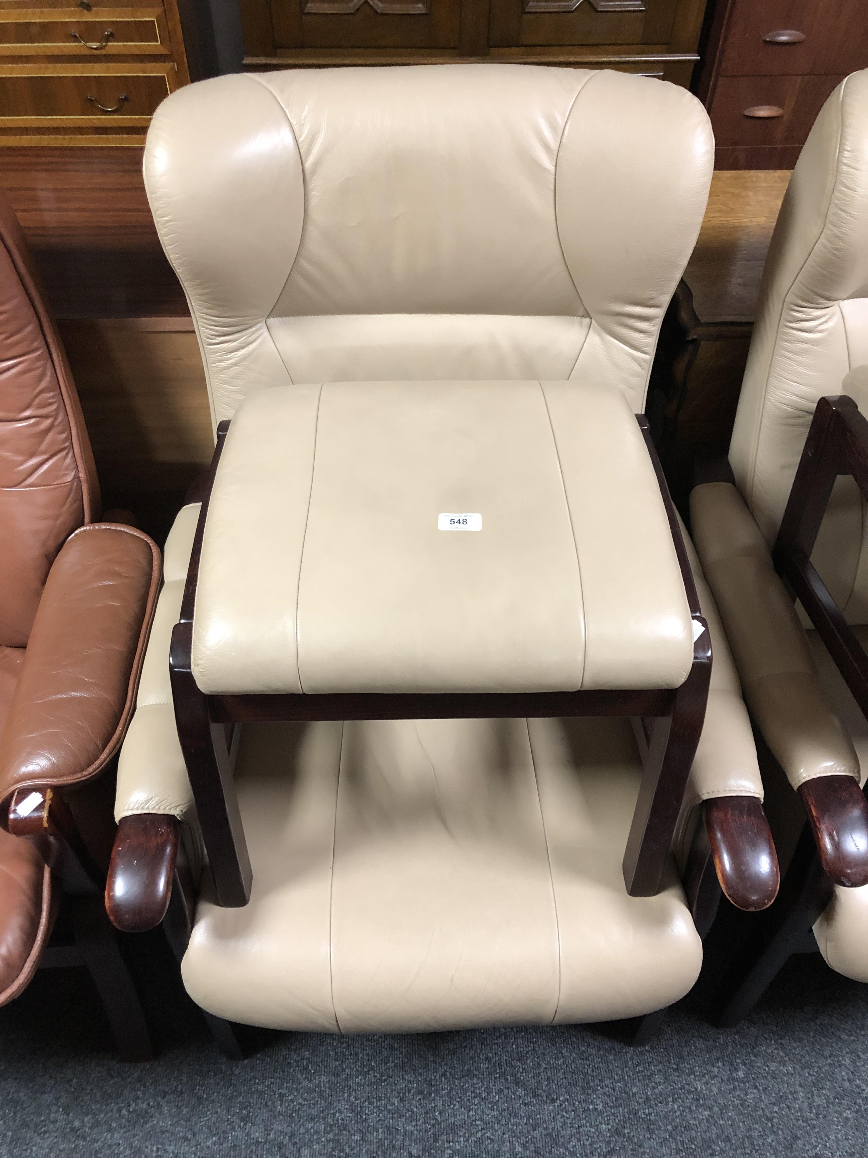 A beech framed cream leather upholstered armchair and matching footstool