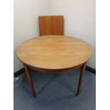 A 20th century circular teak extending dining table with two additional leaves