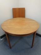 A 20th century circular teak extending dining table with two additional leaves