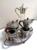 A silver plated serving tray containing four piece pewter tea service and a claret jug