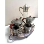 A silver plated serving tray containing four piece pewter tea service and a claret jug
