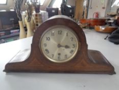 An inlaid oak mantel clock with silvered dial