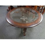 A contemporary circular glass topped coffee table on four way gilt support