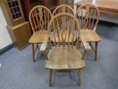 A set of four beech spindle-back dining chairs comprising one carver and three singles