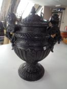 An ornate ebonised pottery lidded urn