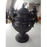 An ornate ebonised pottery lidded urn
