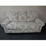 A contemporary three seater settee in grey floral fabric