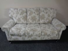 A contemporary three seater settee in grey floral fabric