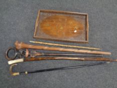 A carved hardwood eastern tray with brass inlay with five assorted sticks including tribal sticks