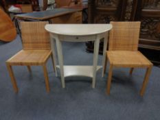 A contemporary D-shaped table with a pair of rattan chairs