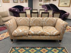 A fine quality three seater sofa upholstered in two-tone fabric, raised on brass castors,