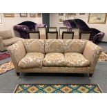 A fine quality three seater sofa upholstered in two-tone fabric, raised on brass castors,