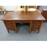 An early 20th century oak writing desk fitted with seven drawers