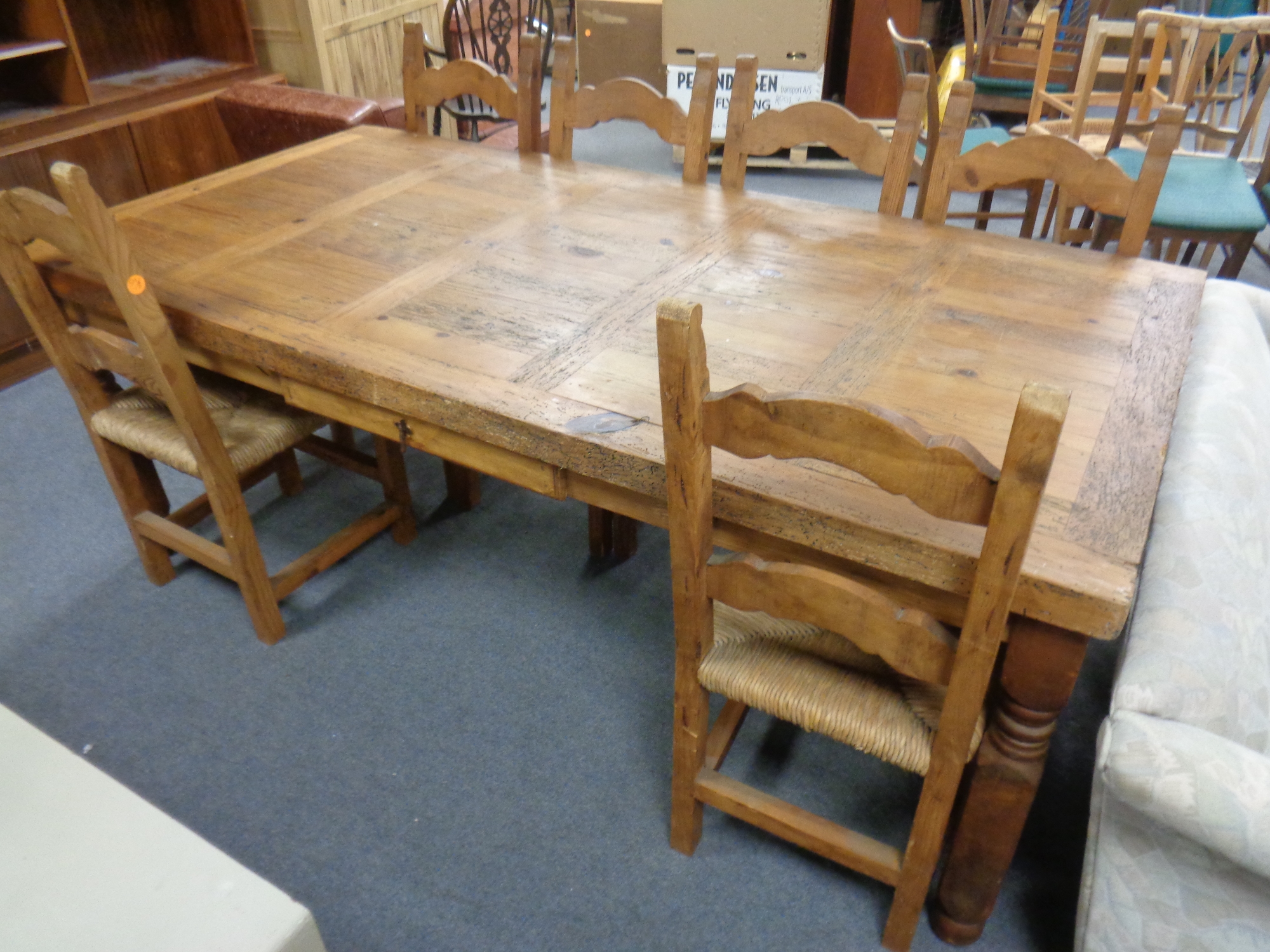 A rustic pine farmhouse style table with a fitted drawer and a set of six rush seated dining chairs