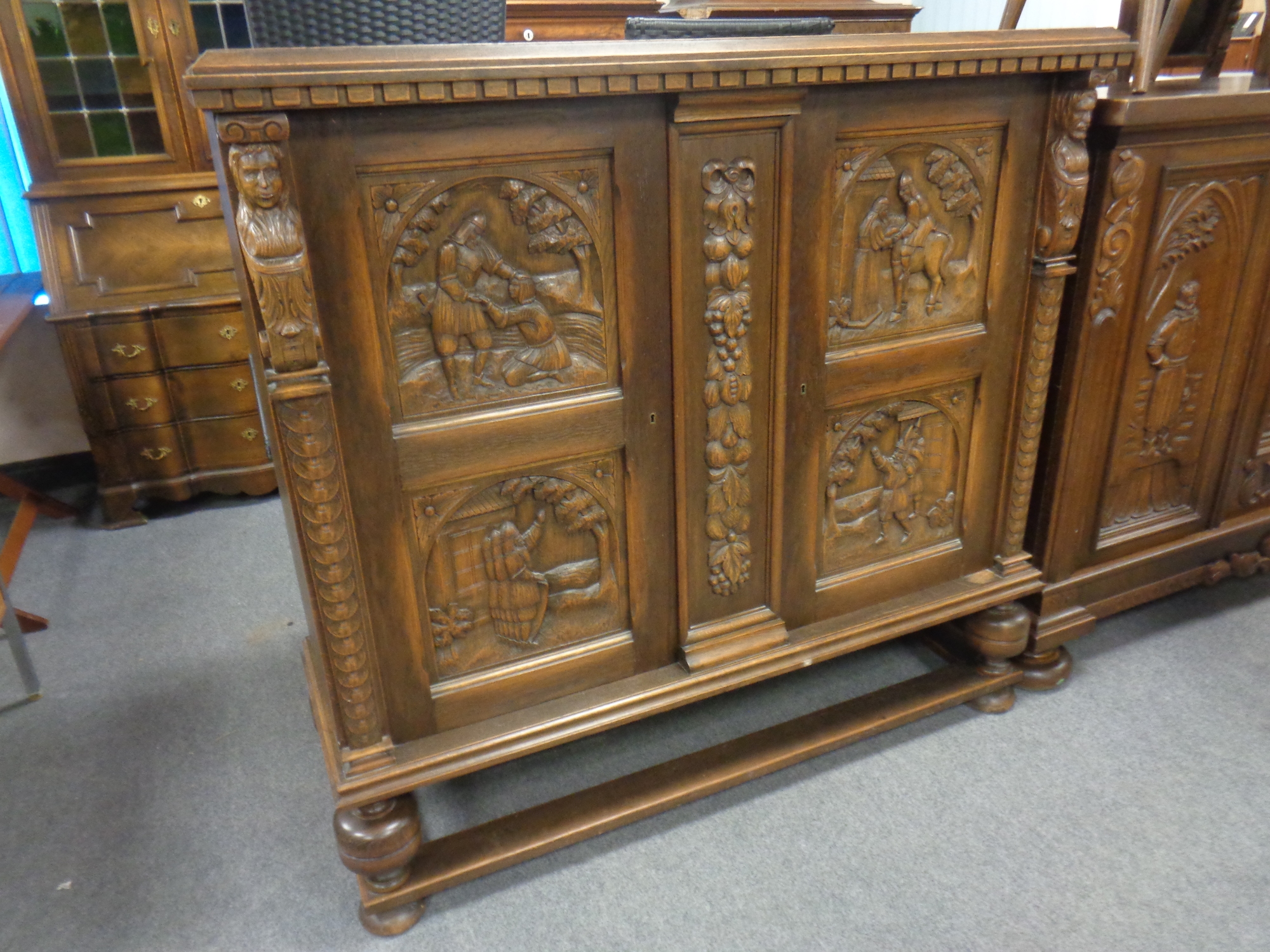 A continental beech side cabinet with carved panel doors