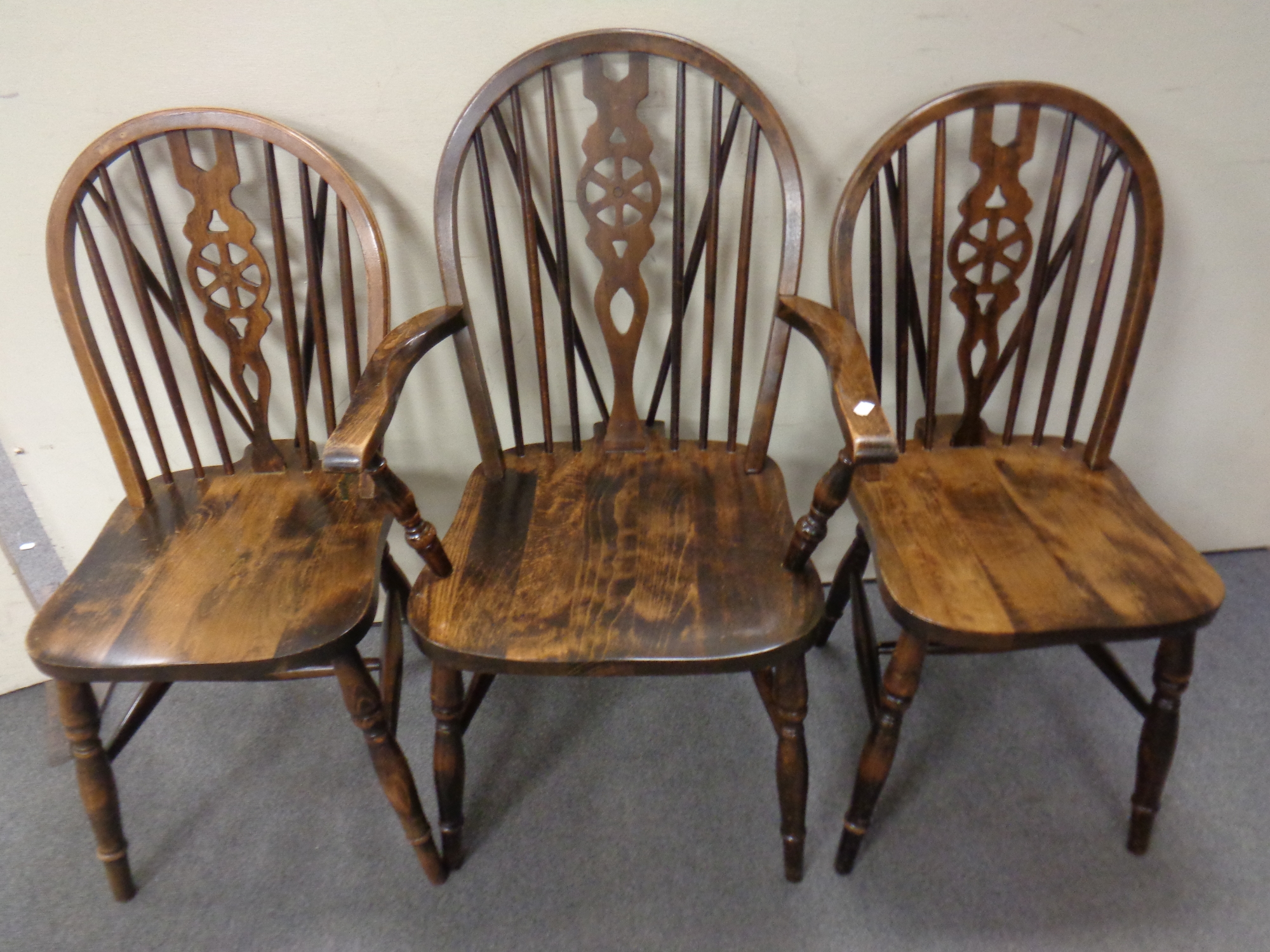 A set of six stained beech wheel back dining chairs comprising two carvers and four singles