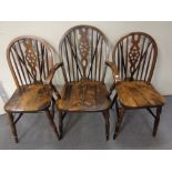 A set of six stained beech wheel back dining chairs comprising two carvers and four singles