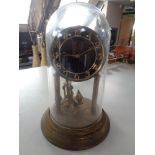 A brass anniversary clock under glass dome